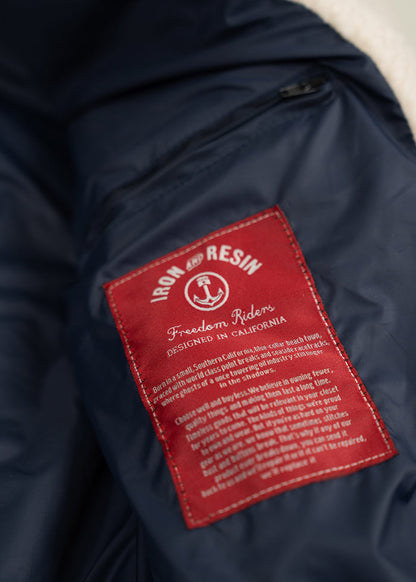 Red "Iron and Resin" label on a navy jacket, reading "Freedom Riders, Designed in California," with detailed text below.